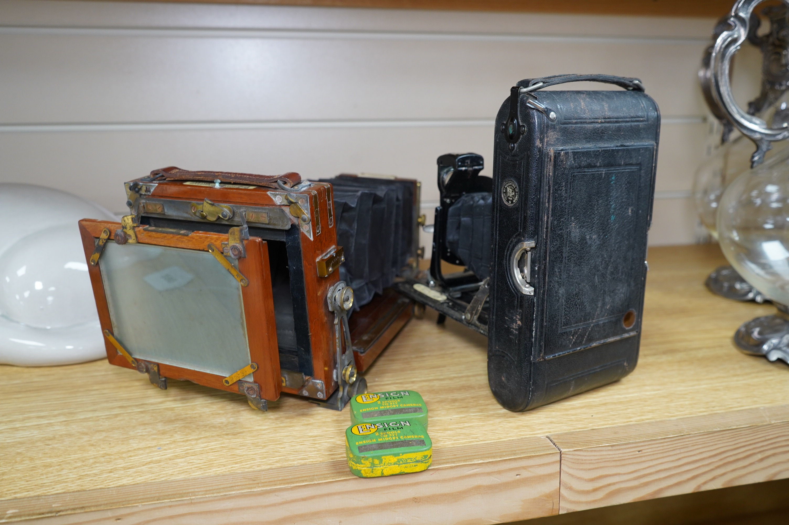 Two cameras; one late 19th century by Lancaster & Son, together with an Ensign bellows camera with two tins of spools of film. Condition - fair to good